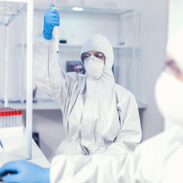 Lab scientist in healthcare lab holding micropipette with sample